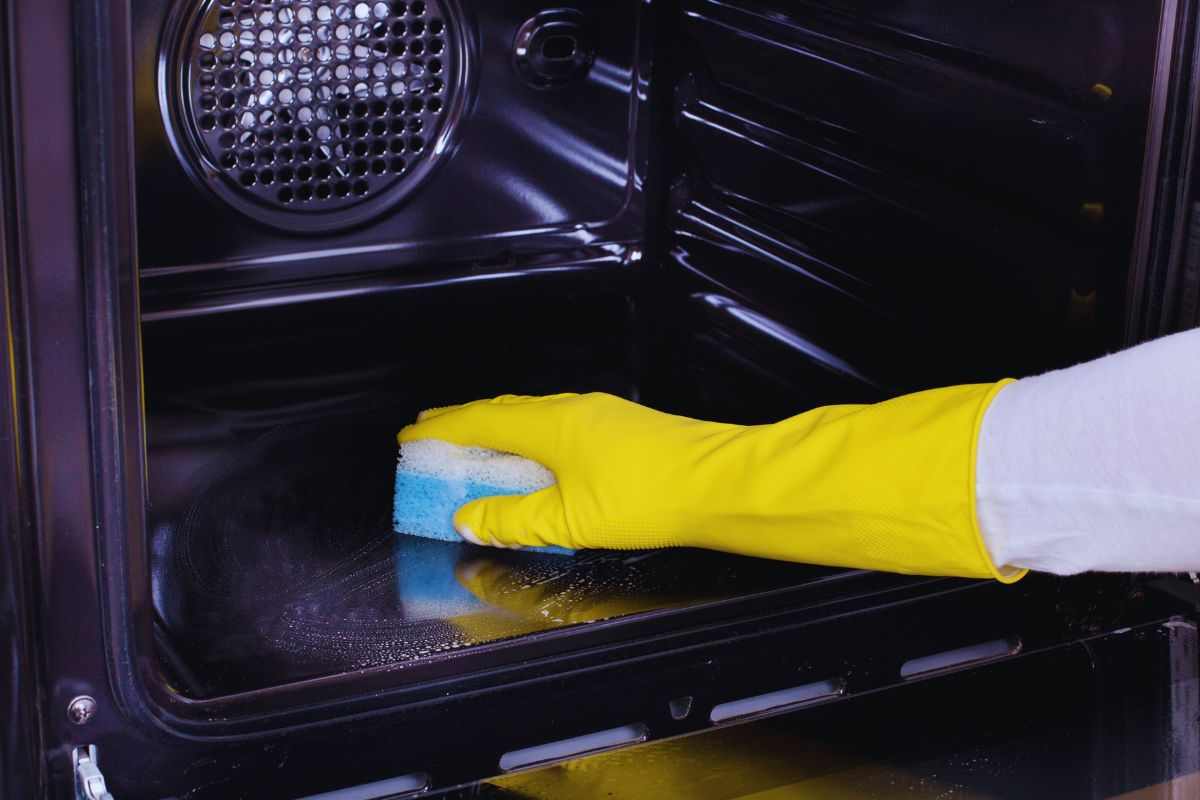 Persona che pulisce l'interno di un forno