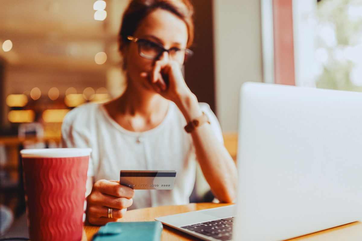 Donna preoccupata davanti a PC con carta di credito in mano