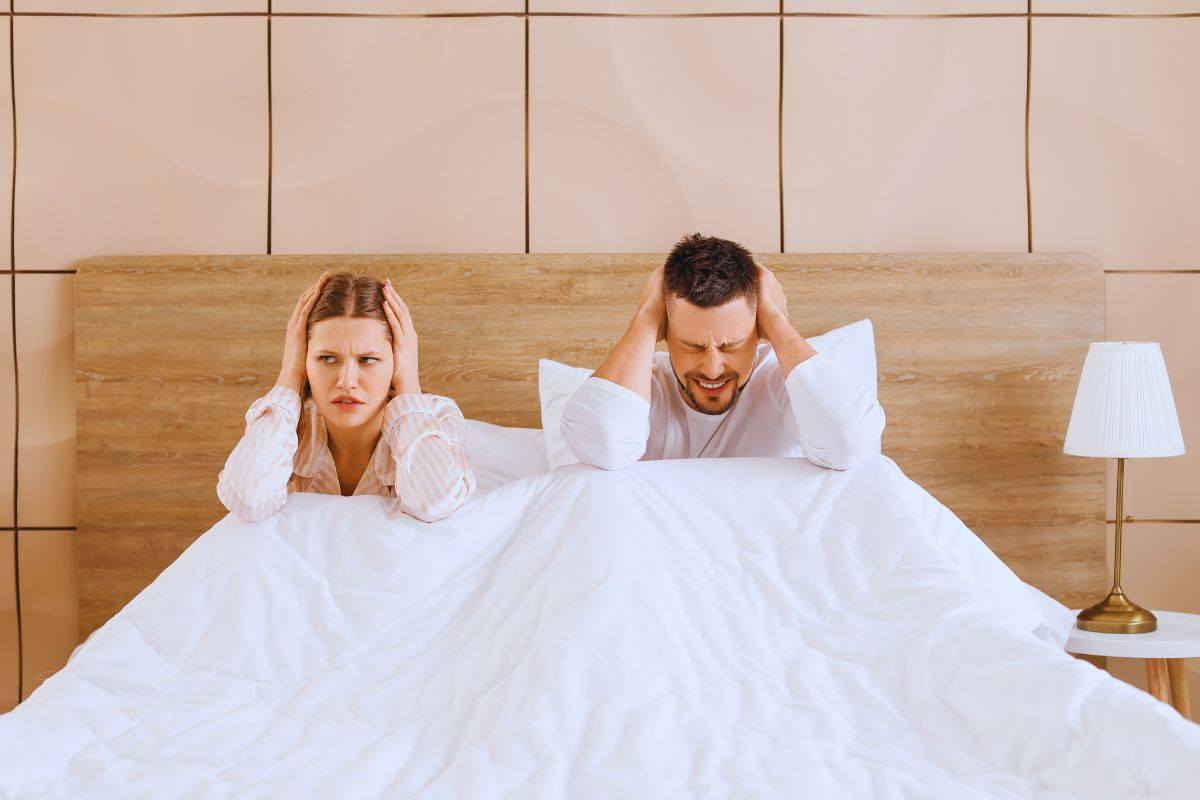 Coppia che si tappa le orecchie a letto a causa del forte rumore