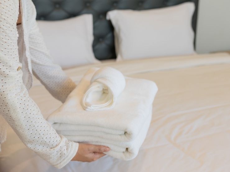 donna che pone asciugamani puliti su un letto