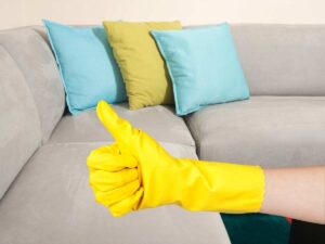 sfondo divano camoscio, primo piano mano con guanto pulizia gesto ok