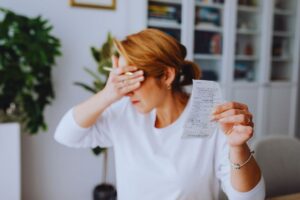 Donna con in mano uno scontrino che si copre gli occhi