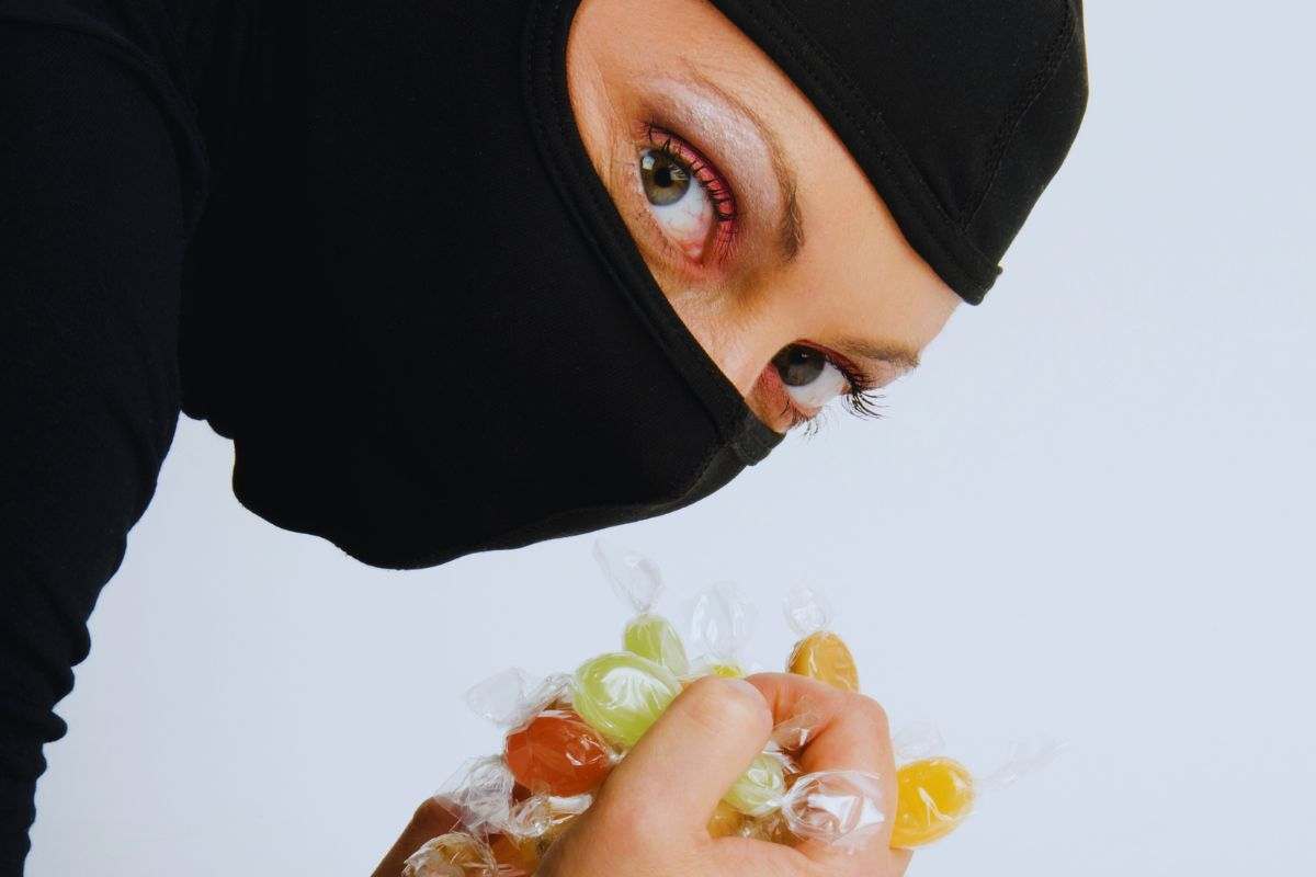 Donna mascherata con caramelle in mano e sguardo terrorizzato