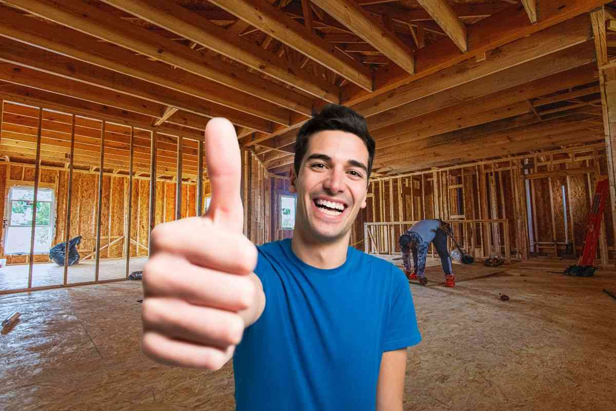 Uomo che mostra il pollice all'in sù e operai che lavorano sulle fondamenta di una casa