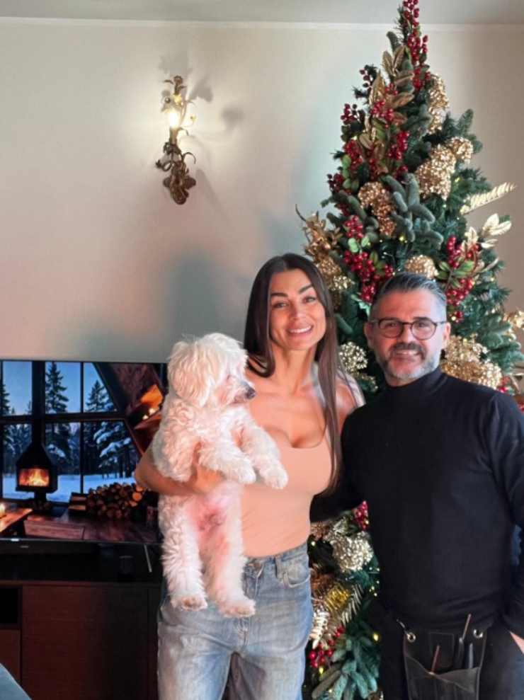 Elga Enardu con in braccio il cagnolino di casa e accanto Enrico Curreri, l'autore delle decorazioni natalizie che si vedono alle loro spalle.