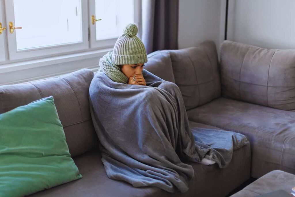 Donna su divano completamente avvolta da una coperta