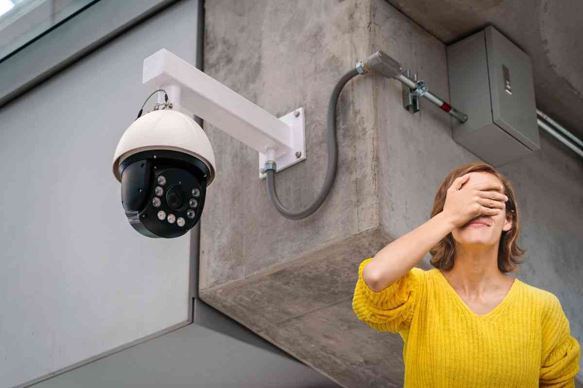 Telecamera di sicurezza installata su muro e donna che si copre la faccia con la mano