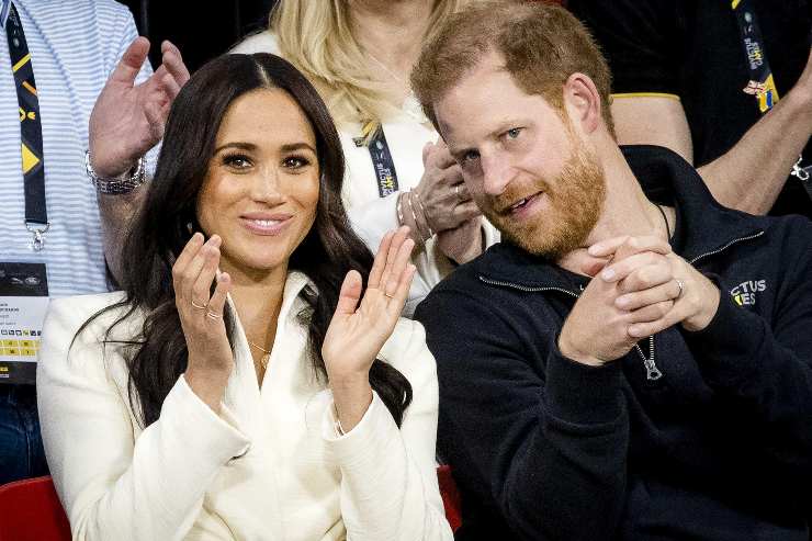 Harry e Meghan che scherzano sugli spalti di un palazzetto sportivo