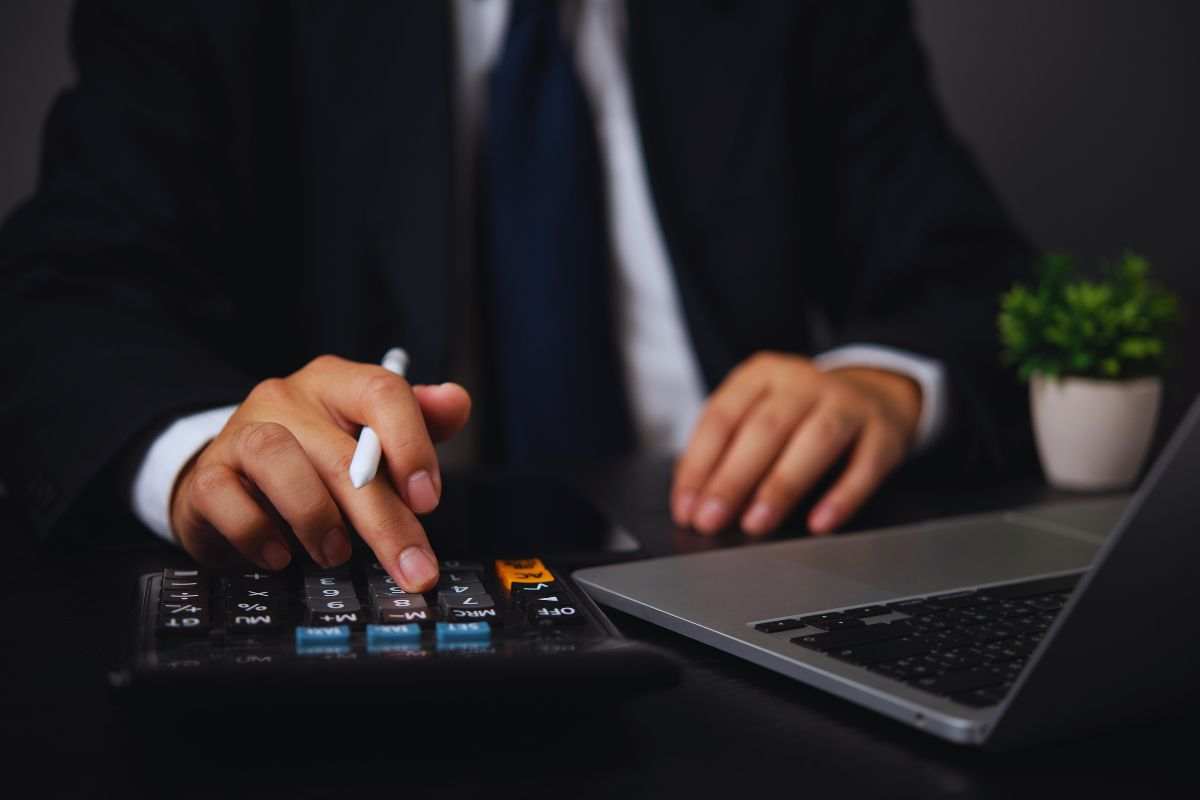 Uomo in abiti eleganti che lavora in scrivania con computer e calcolatrice