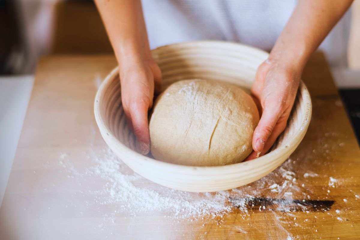 Donna che impasta in una ciotola poggiata su tavolo in legno