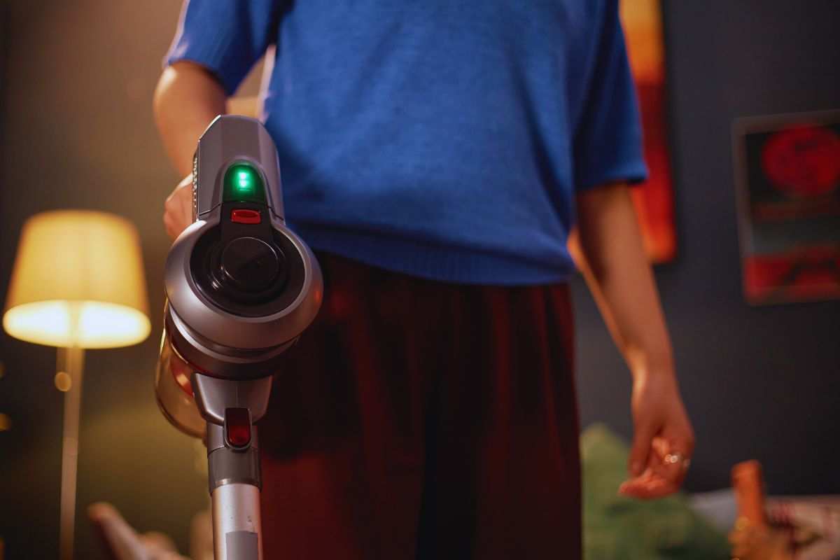 Persona che utilizza un aspirapolvere senza fili