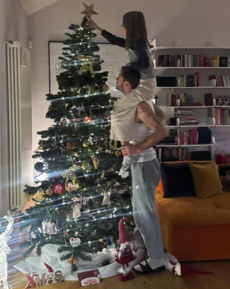 Cattelan che aiuta la figlia a porre il puntale sull'albero di Natale