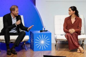 Harry e Meghan che parlano dal palco di un evento benefico