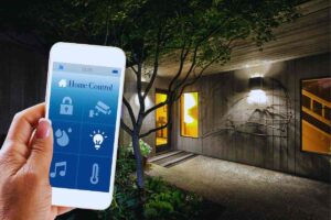 Persona che utilizza smartphone per gestire l'illuminazione di casa da fuori e ingresso abitazione illuminato