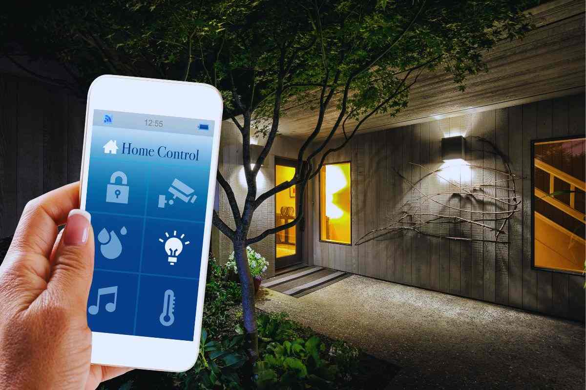 Persona che utilizza smartphone per gestire l'illuminazione di casa da fuori e ingresso abitazione illuminato