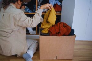 Donna che mette i vestiti in esubero in uno scatolo