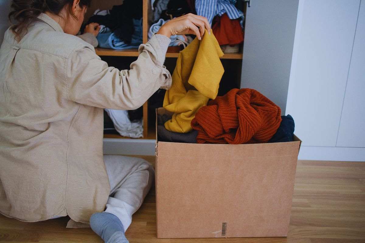 Donna che mette i vestiti in esubero in uno scatolo