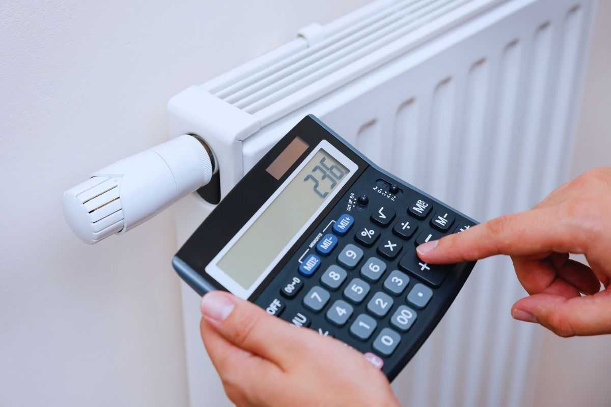 Uomo che effettua calcoli con calcolatrice davanti ad un termosifone