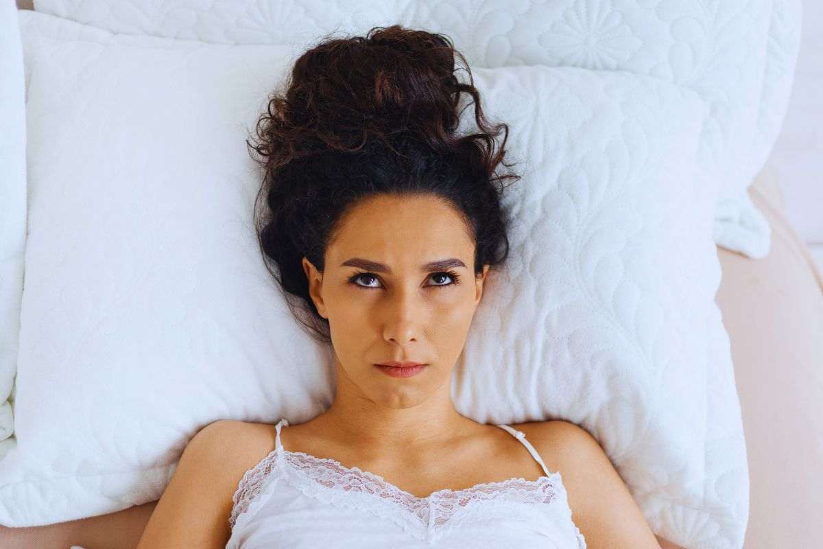 Donna stesa a letto con espressione infuriata