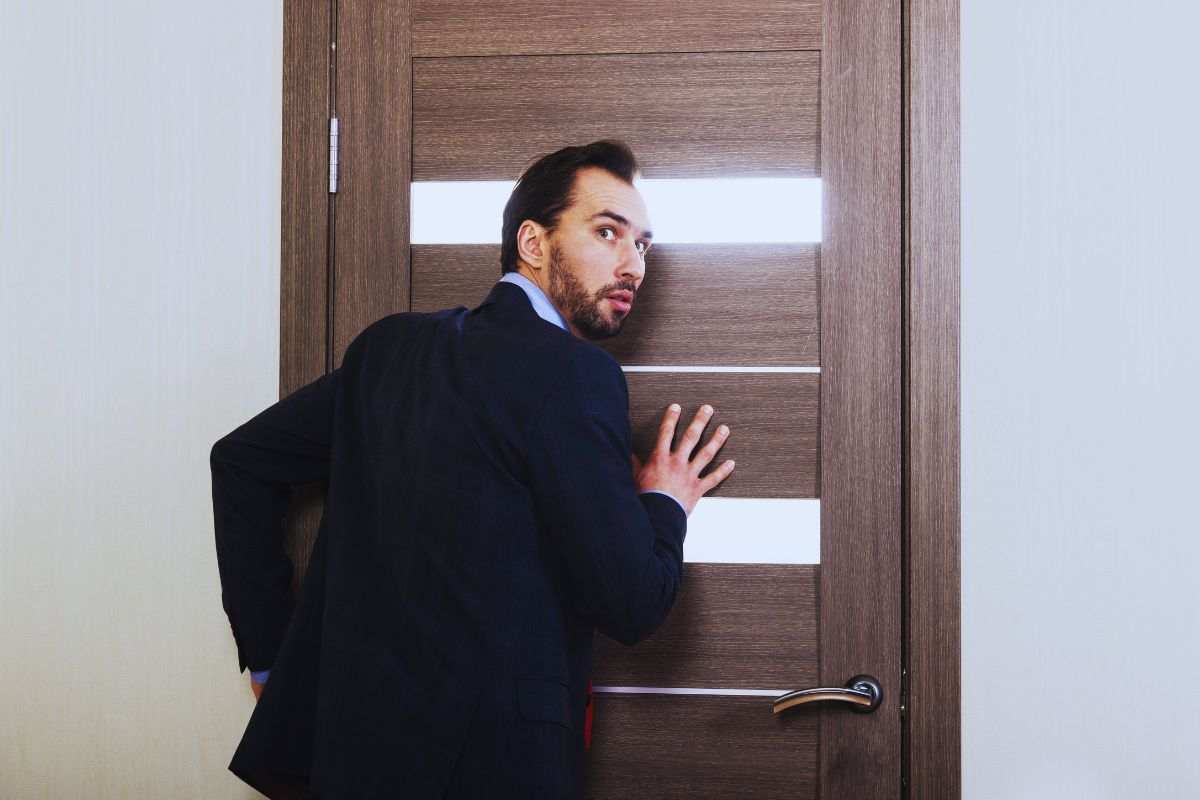 Uomo che poggia orecchio alla porta per ascoltare