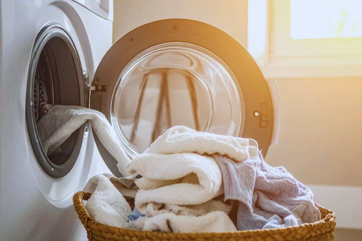 Panni dentro una cesta posta accanto ad una lavatrice aperta
