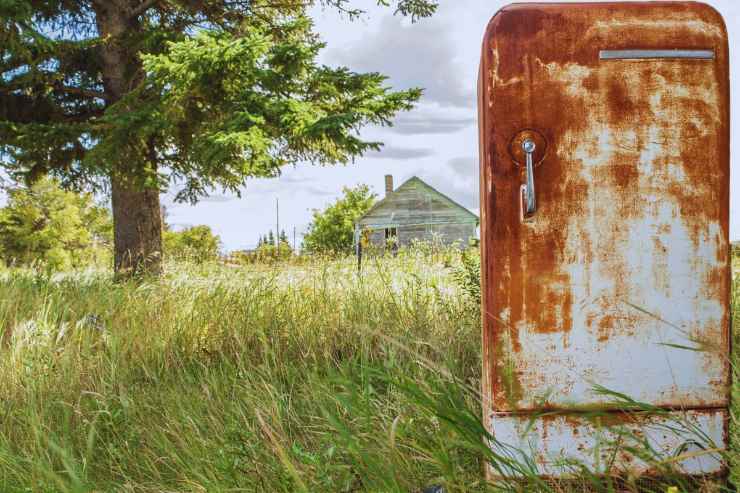 Vecchio frigo arrugginito abbandonato in un prato