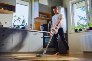 Uomo che utilizza aspirapolvere su tappeto