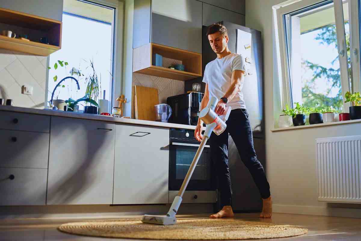 Uomo che utilizza aspirapolvere su tappeto