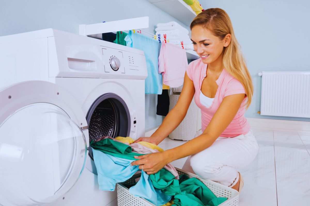 Donna sorridente che estrae i panni puliti dalla lavatrice