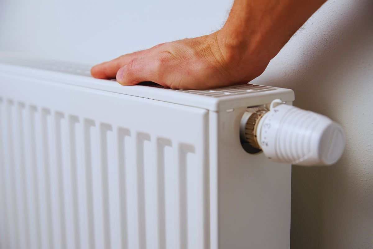 Uomo che poggia la mano sul termosifone per verificare che stia funzionando