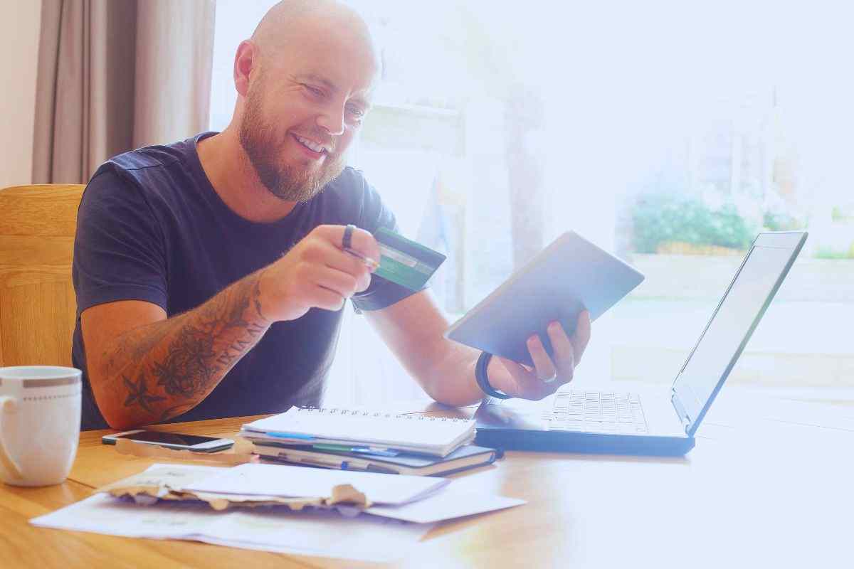 Uomo contento con carta di credito e tablet in mano