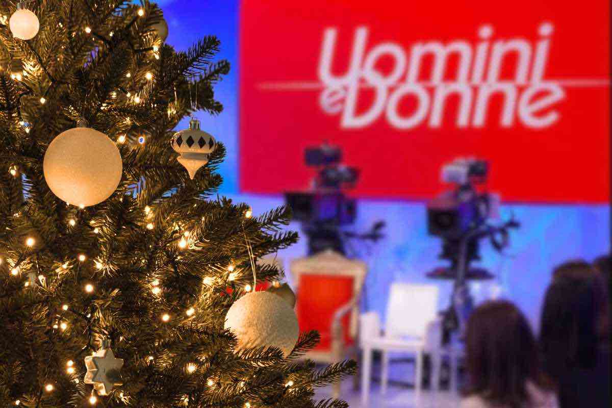 studio di uomini e donne sullo sfondo, albero di natale con palline bianche in primo piano